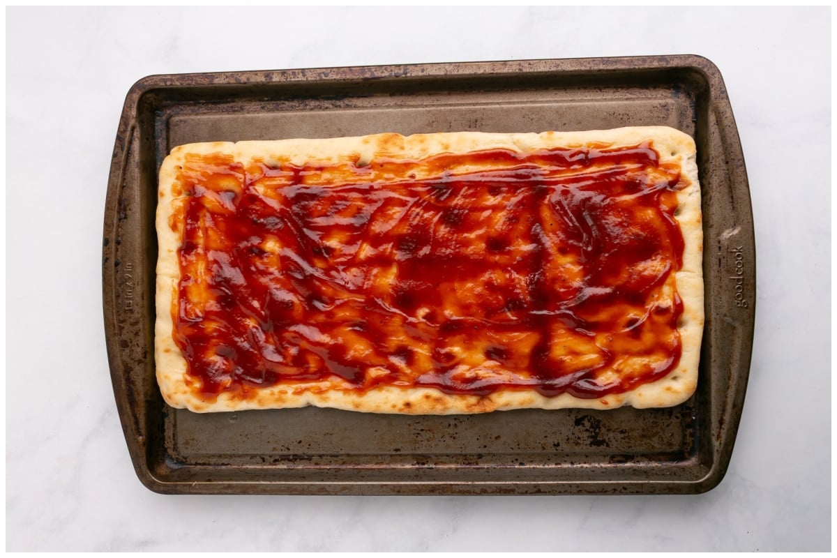 A tray with flatbread brushed with bbq sauce.