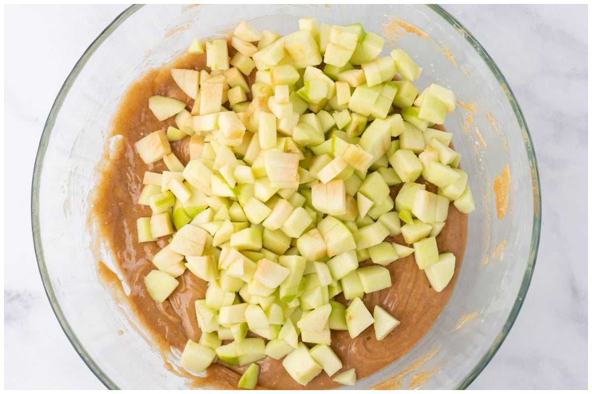 A bowl of cake mixed with apple cubes.