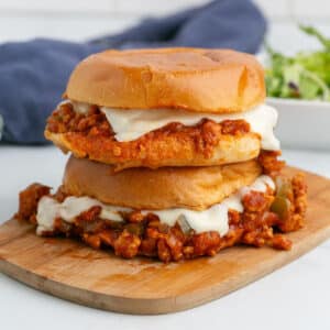 Chicken sloppy joes sandwiches stacked on a cutting board.