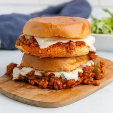Chicken sloppy joes sandwiches stacked on a cutting board.