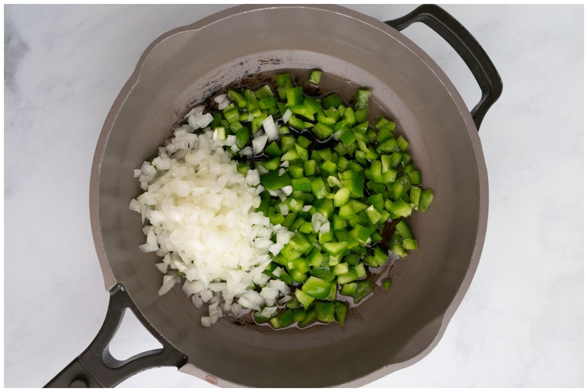 A large skillet with onion and bell pepper.