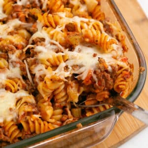 A zoomed in image on a serving spoon with some pasta bolognese.