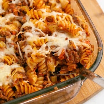 A zoomed in image on a serving spoon with some pasta bolognese.