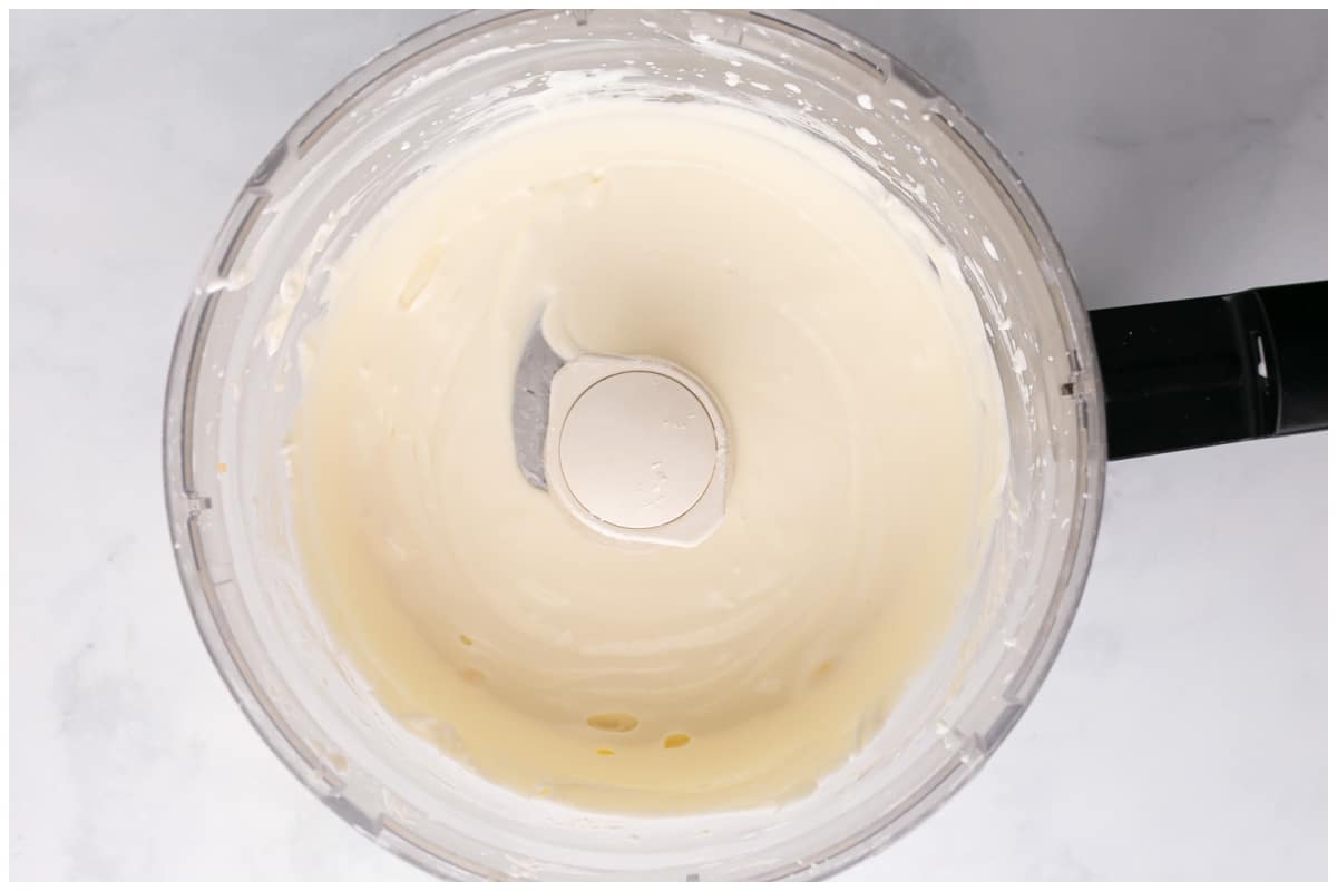 Creamy cheese mixture in the bowl of a mini food processor.