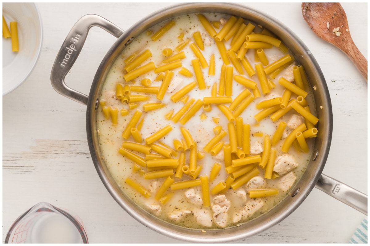Pasta with chicken and milk in a large skillet.