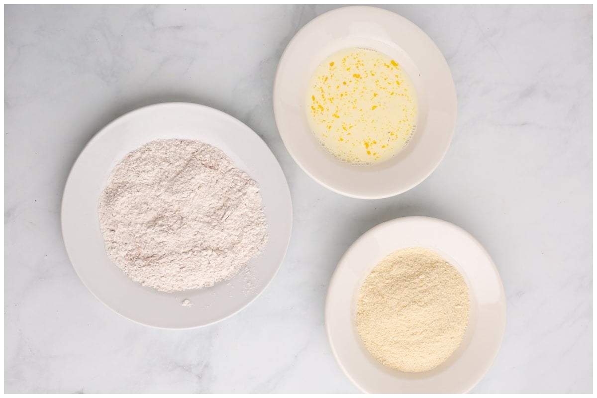Three bowls of eggs, flour mixture and crushed crackers.