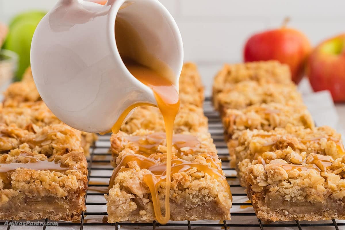 Pouring salted caramel sauce over apple pie bars.