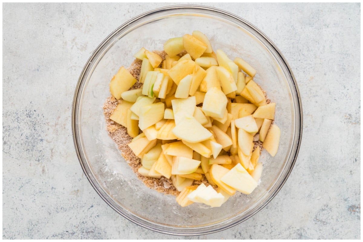 Sliced apples with the filling ingredients in a glass bowl.