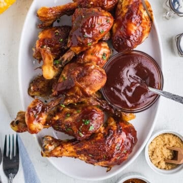 Overhead image of bbq drumsticks on a white platter.