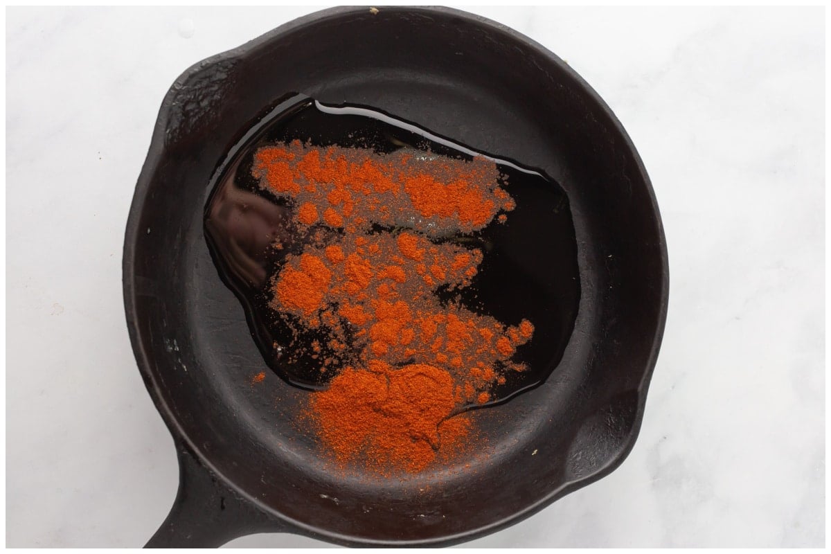 A skillet with paprika and oil.