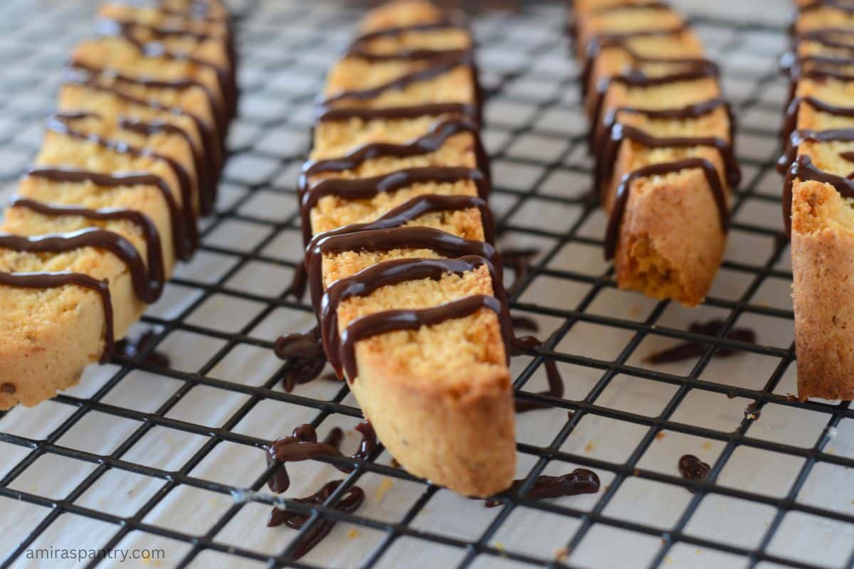 Biscotti on a wire rack drizzled with chocolate.