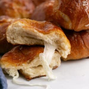 Two halves of a ball of pretzel stacked with the cheese oozing out of the top one.