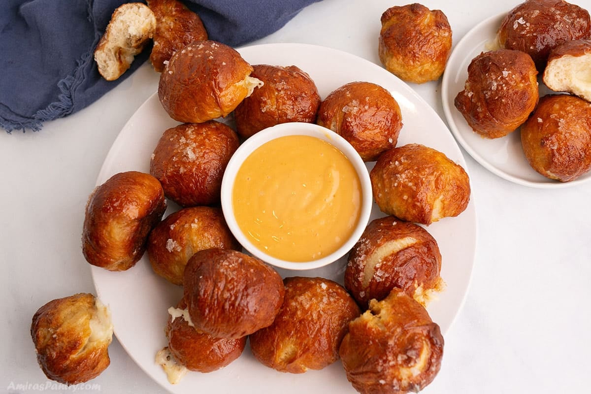 Cheese Pretzel balls on a white platter with cheese dip in the center.