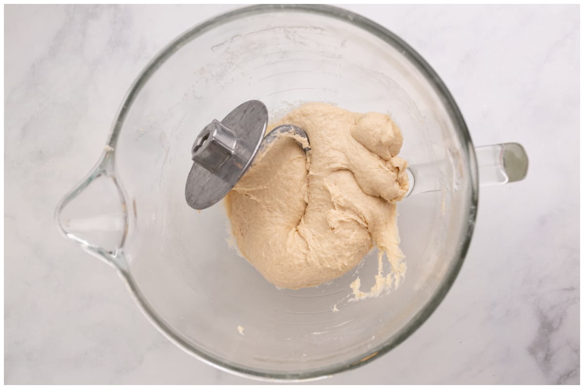 A stand mixer bowl with dough and a dough hook.