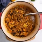 An overhead image for chicken tagine with apricots with a spoon in the pot.