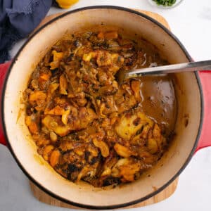 An overhead image for chicken tagine with apricots with a spoon in the pot.