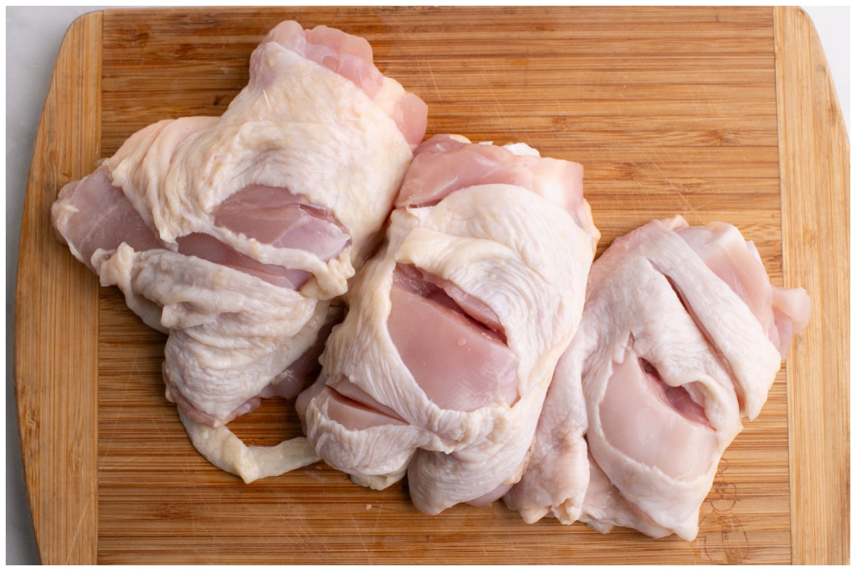 Chicken thighs on a wooden board.