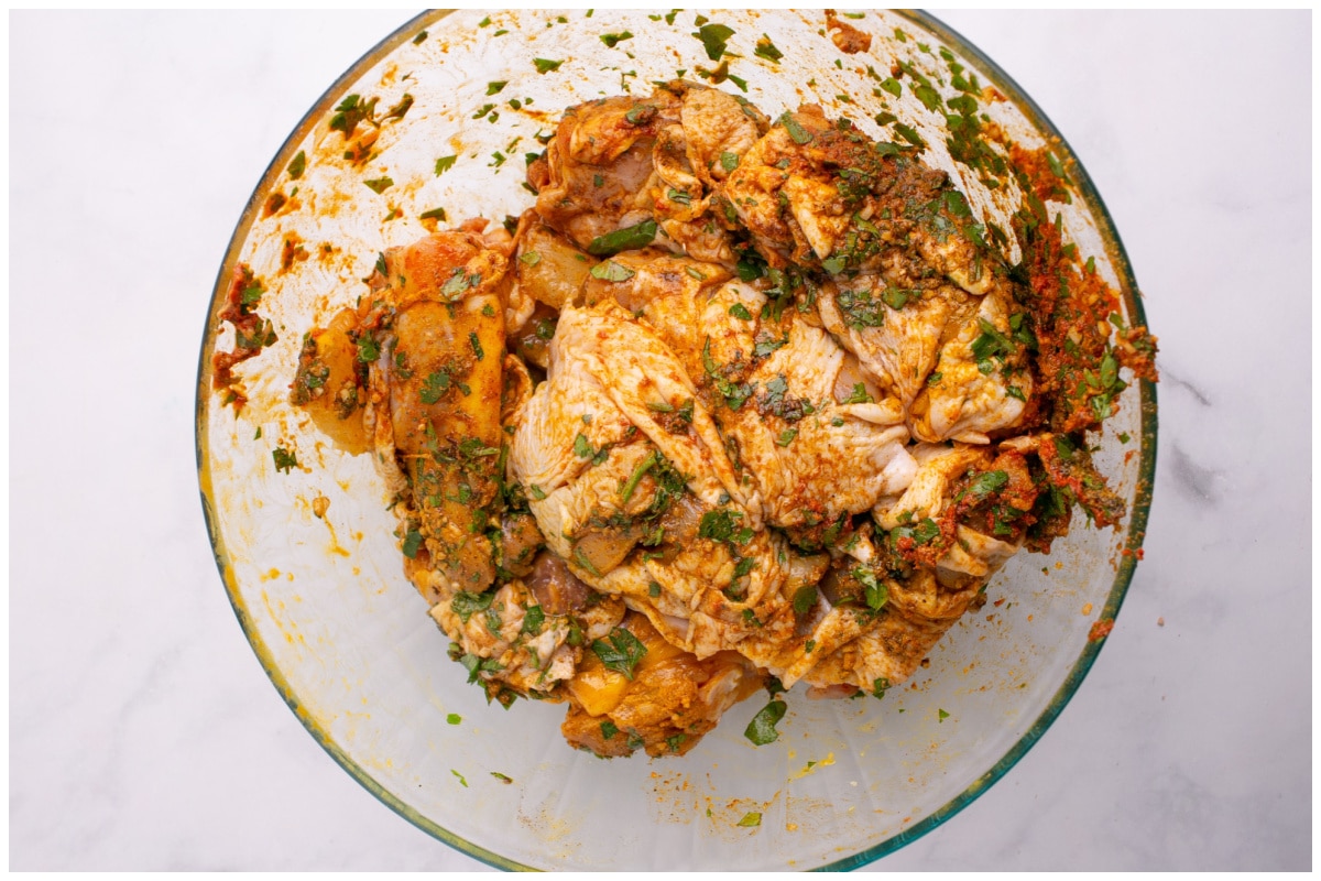 Chicken thighs covered in marinade in a glass bowl.