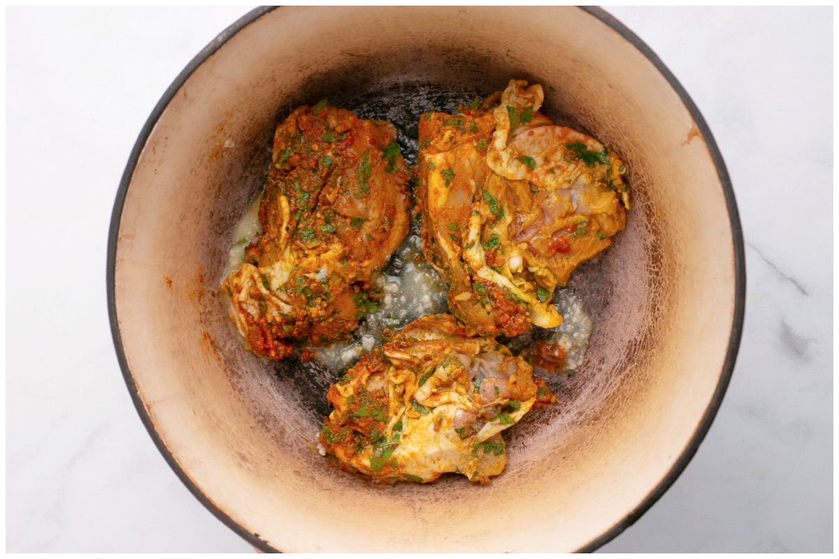 Chicken thighs searing in a deep pot.