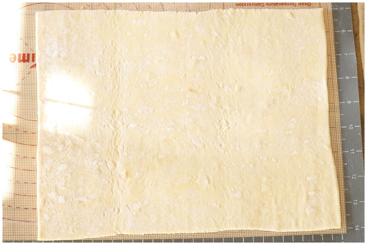 A sheet of puff pastry rolled on a baking mat.