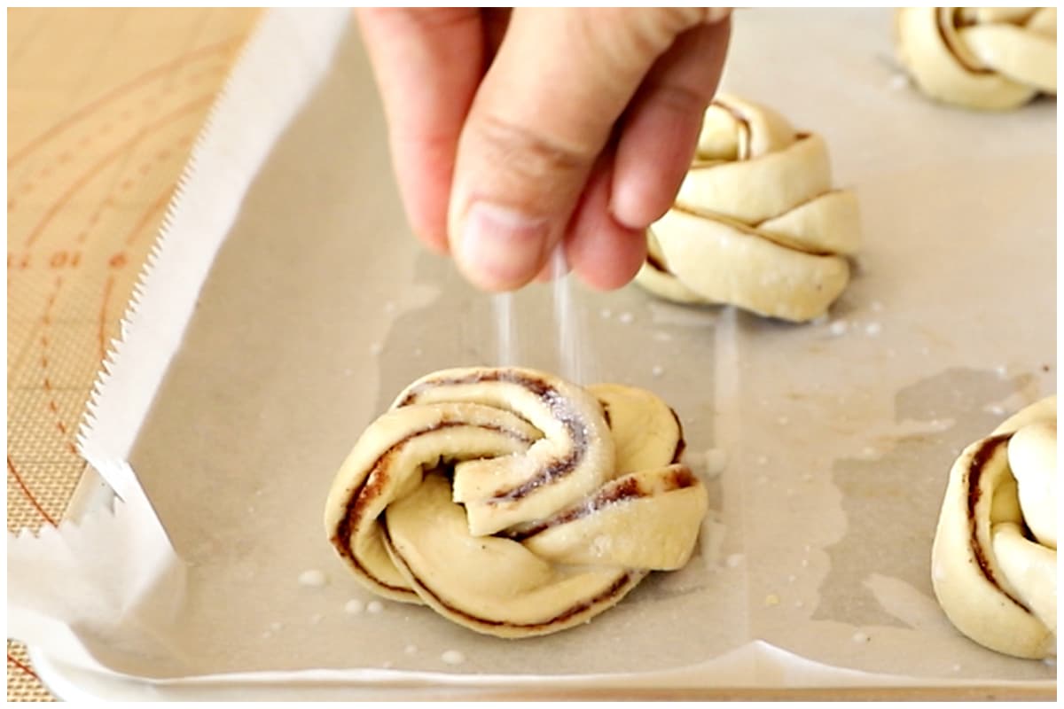 Sprinkling some granulated sugar over the puff swirls.