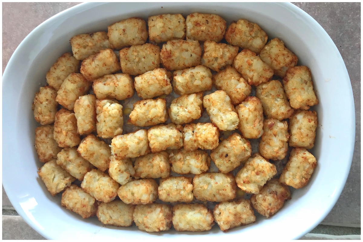 A wgite ceramic casserole dish with tater tots.