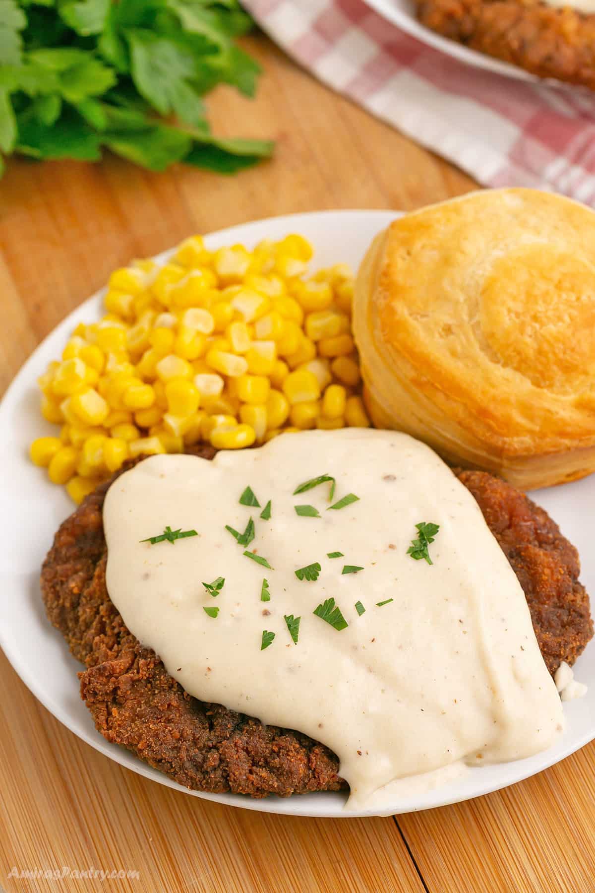 A fried steak on a white plate with gravy.