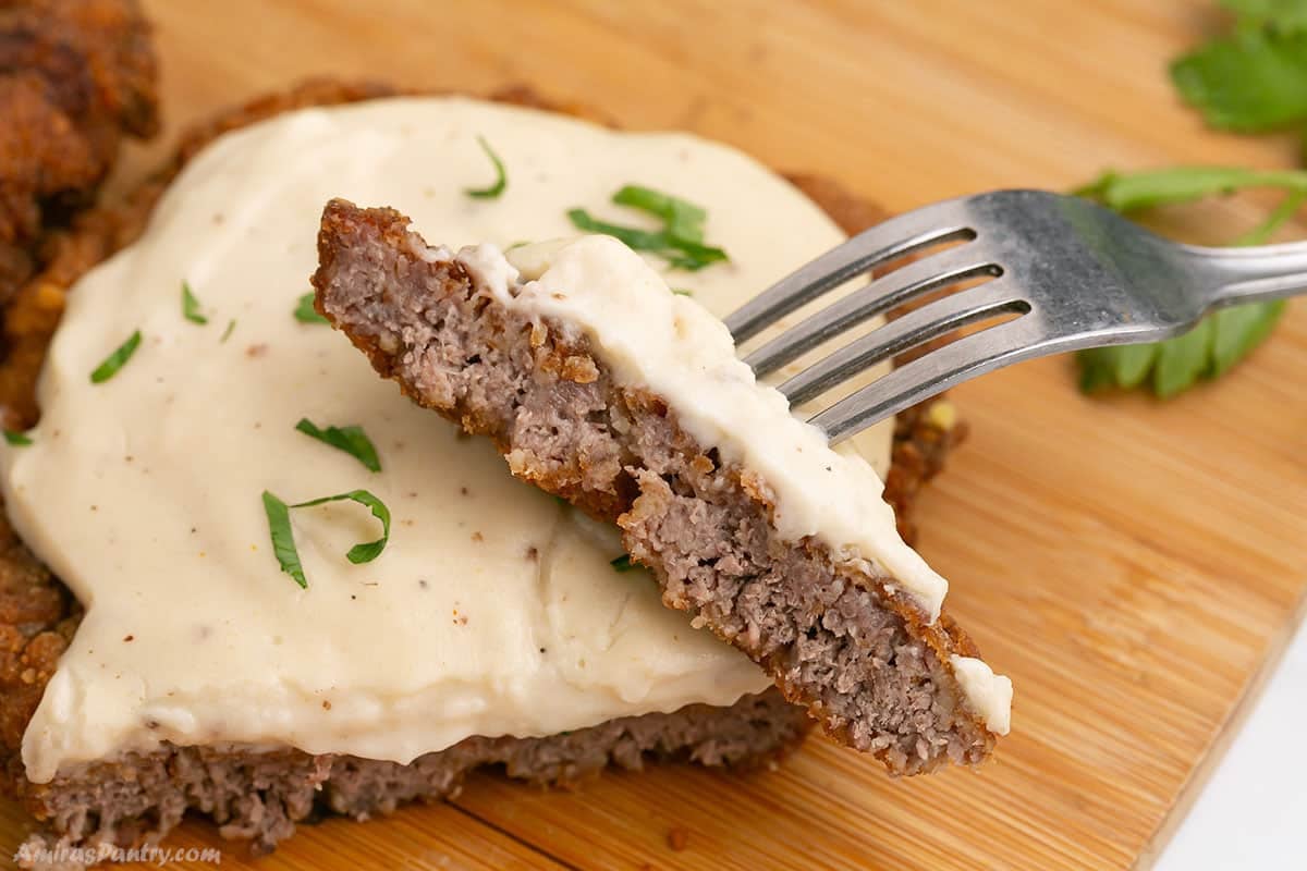 A fork with a piece of fried steak cut to show texture.