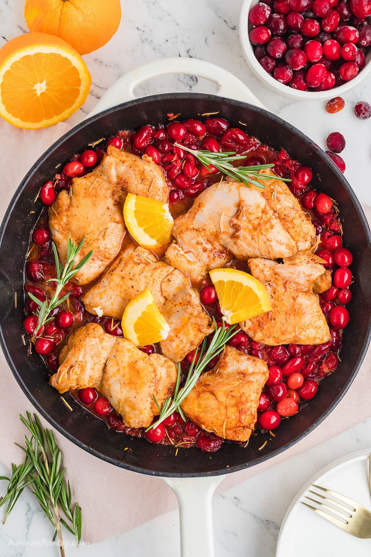 Cranberry chicken with orange slices on a large skillet.