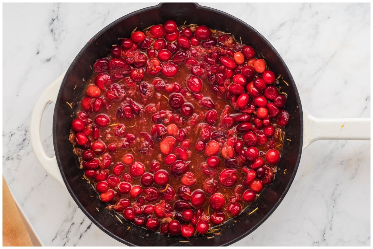 Cooked cranberries in a skillet with sauce.