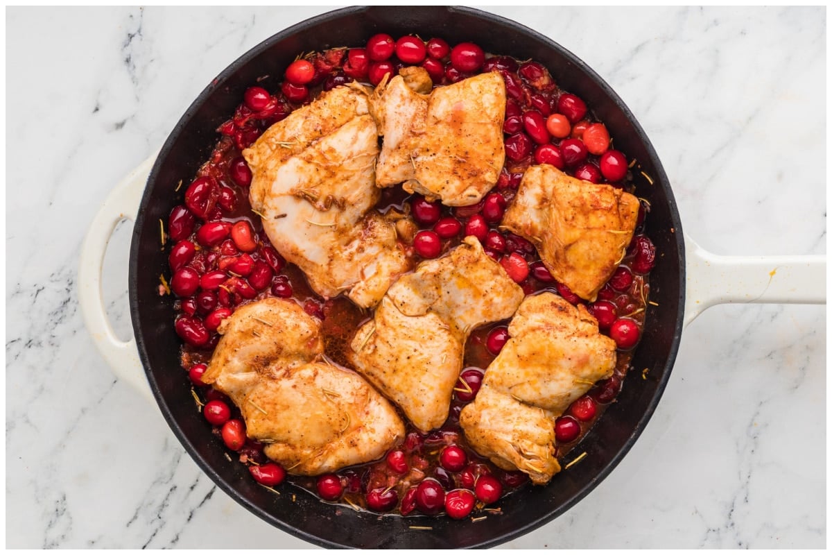 An overhead image for a skillet with chicken nestled in cranberry sauce.