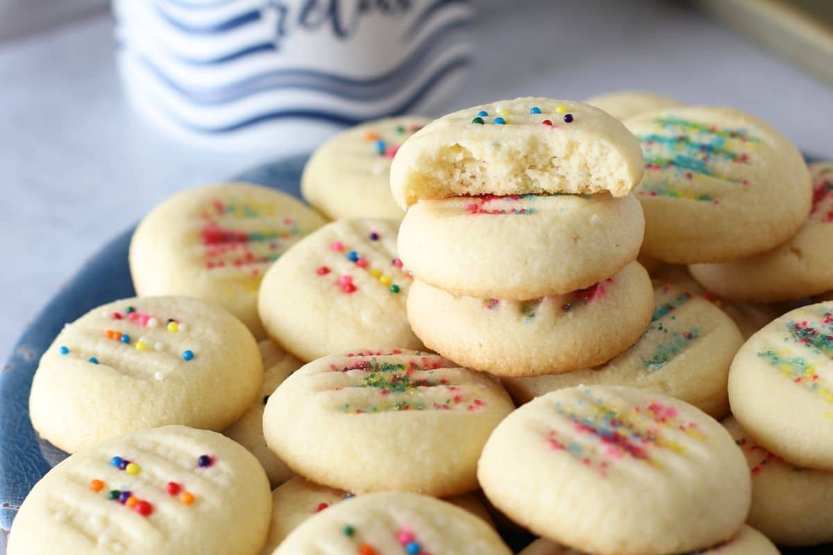 Cookies piled on a blue serving plate with a bite taken from one to show texture.