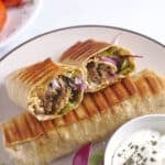 Two doner wraps on a plate with one cut in half to show texture.
