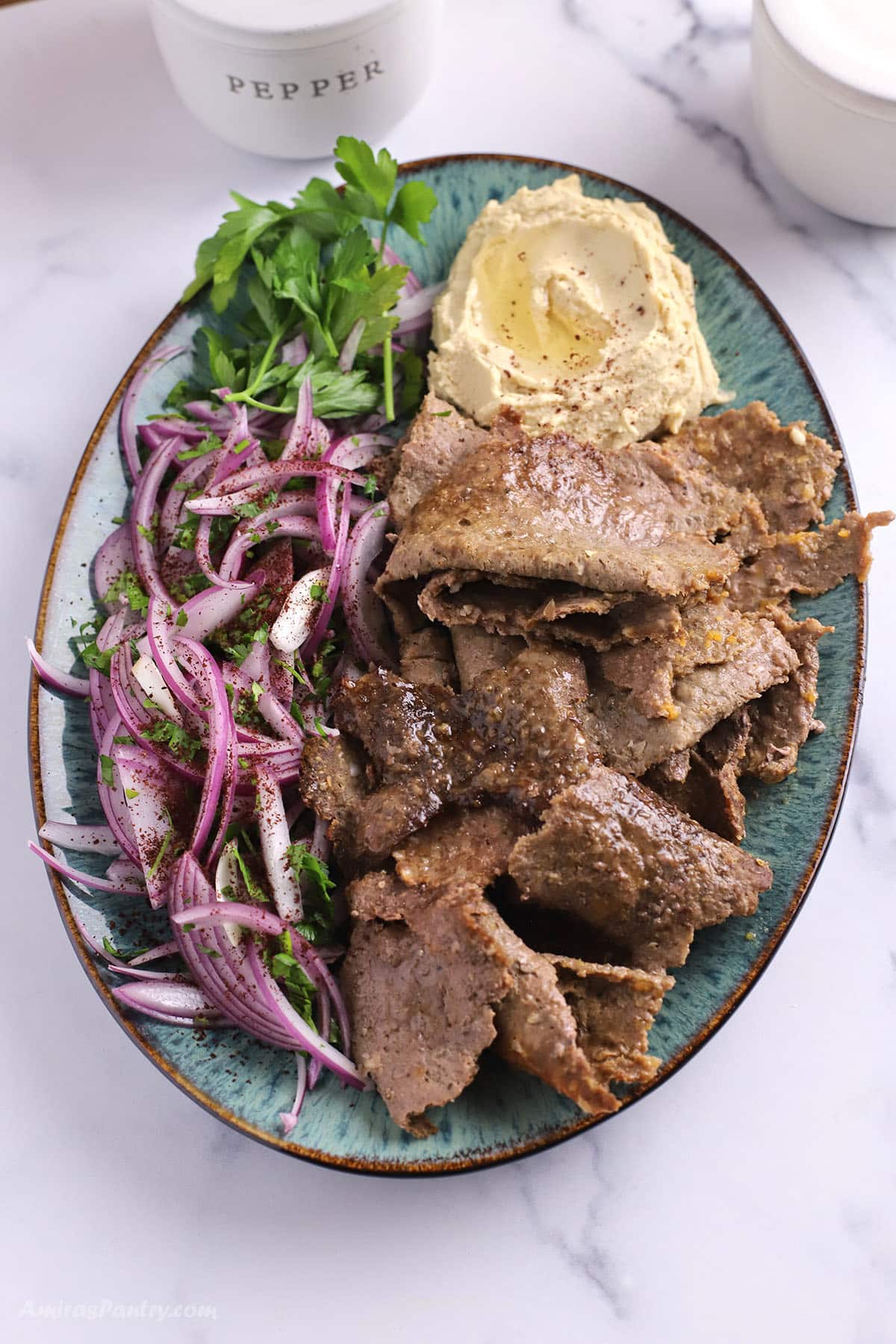A serving platter with Doner meat, hummus and Turkish onion salad.