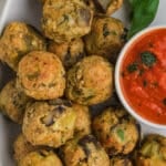 Eggplant meatballs on a platter with a dipping sauce on the side.