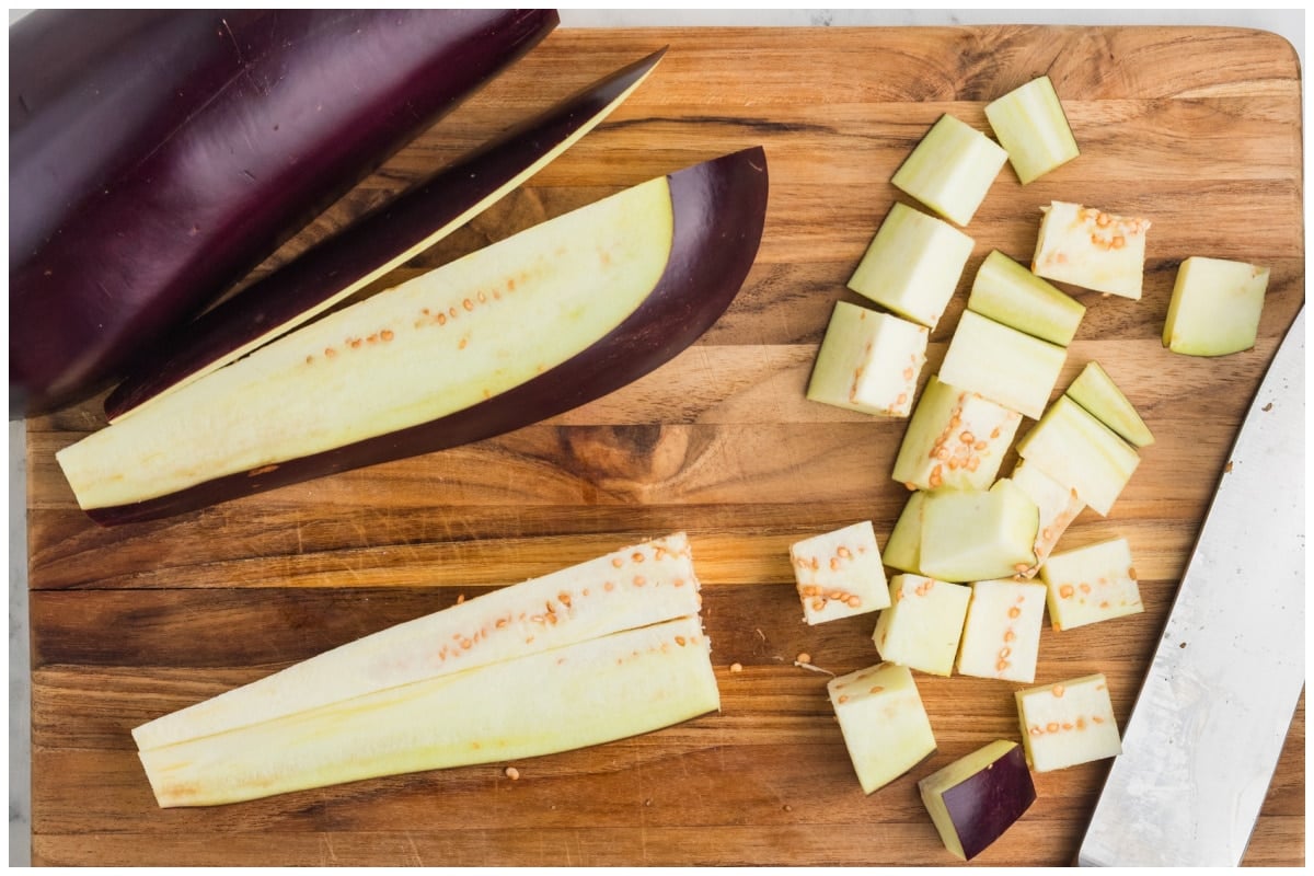 Eggplant cubed on a wooden cutting board.