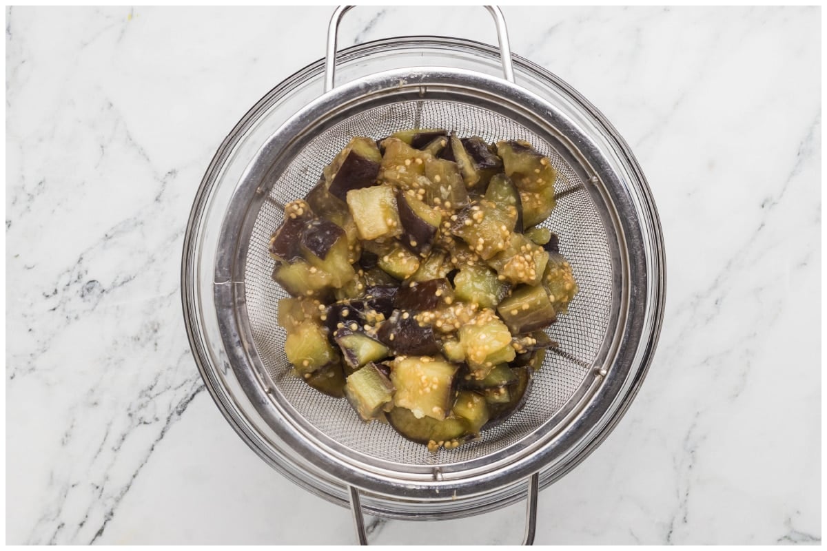 Cooked eggplants in a large colander.