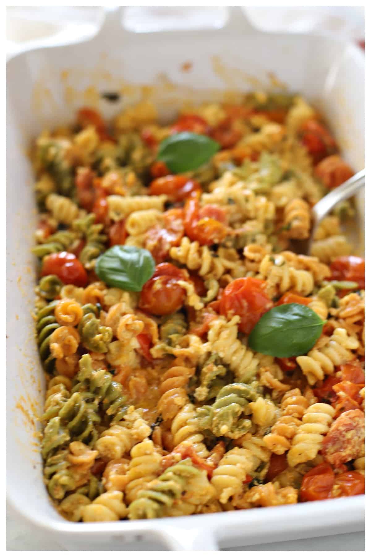 Feta pasta in a white casserole dish with a spoon in it.