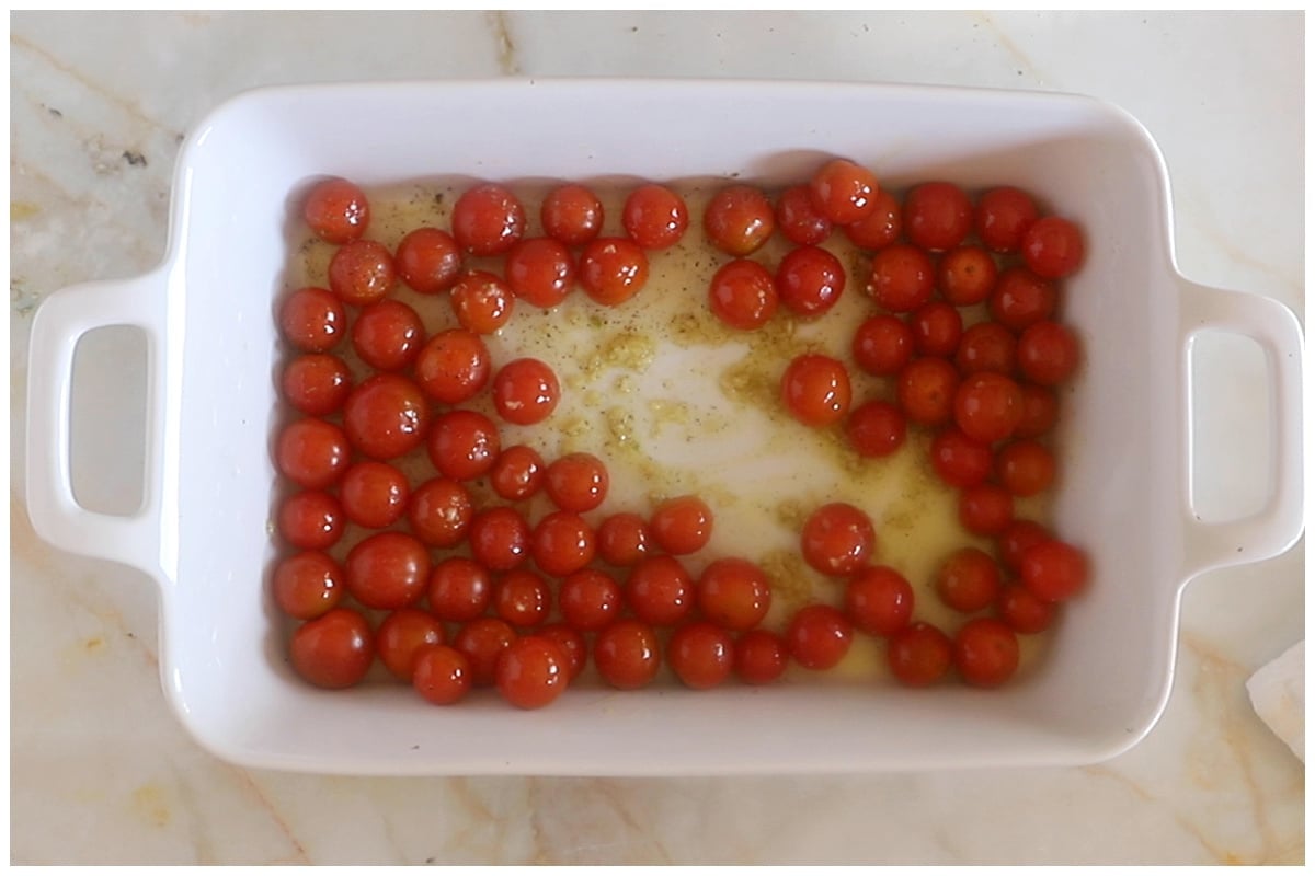 Cherry tomatoes with oil, garlic and spices in a white ceramic dish.