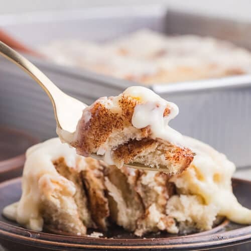 A fork with a bite of cinnamon roll.