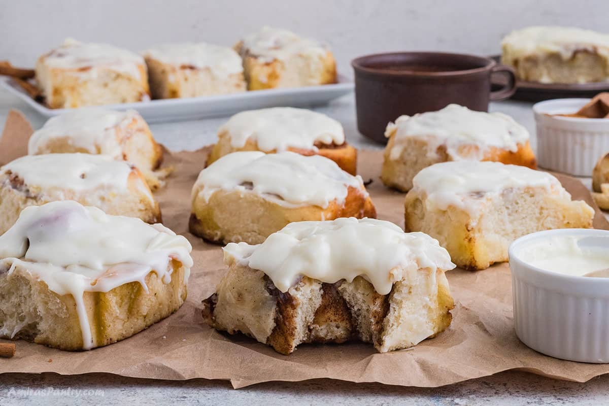 Frosted cinnamon rolls on parchment papers.