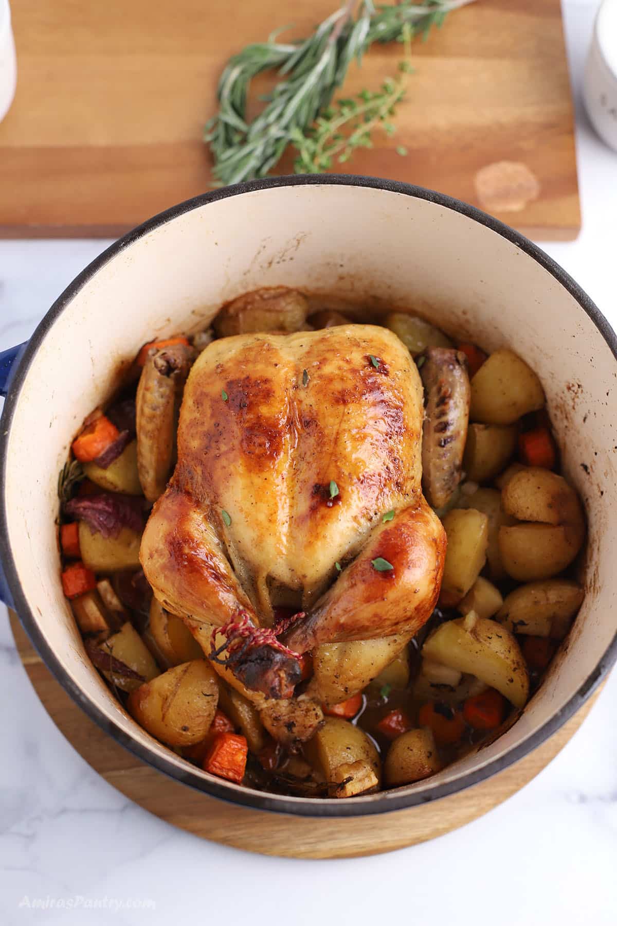 An overhead image of a roast chicken in a large dtuch oven.