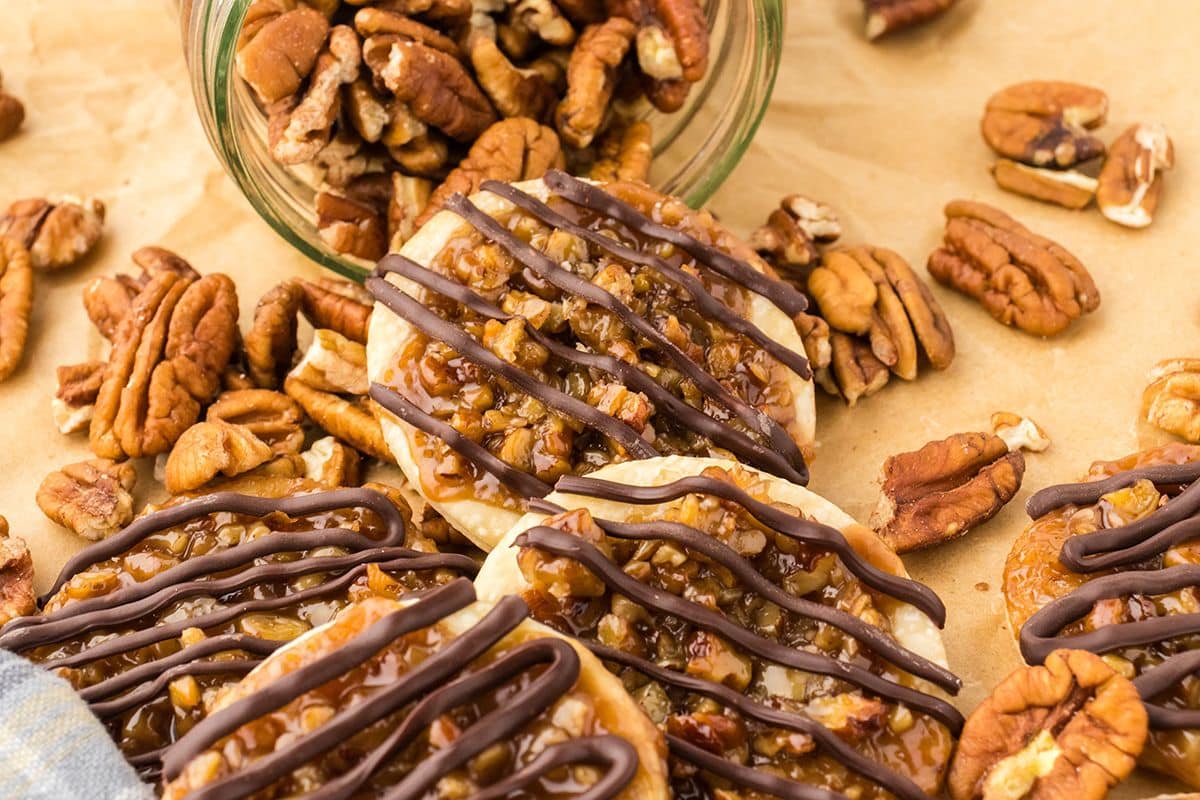 Pecan pie cookies on a brown parchment paper with pecans on the table.