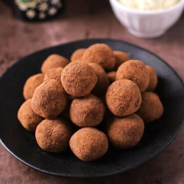 A black serving platter with a pile of tiramisu balls.