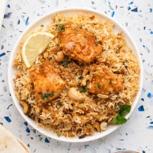 A large platter with Biryani rice topped with chicken tikka.