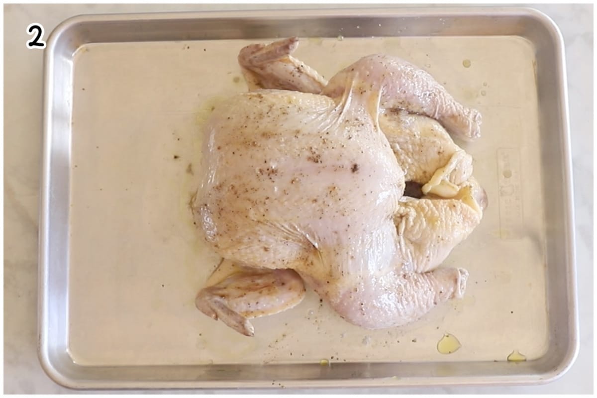 A whole chicken on a baking dish sprinkled with salt and black pepper.