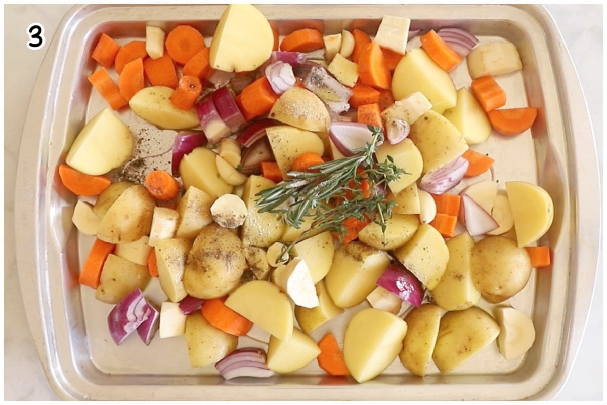 Vegetables on a baking tray mixed with oil and aromatics.