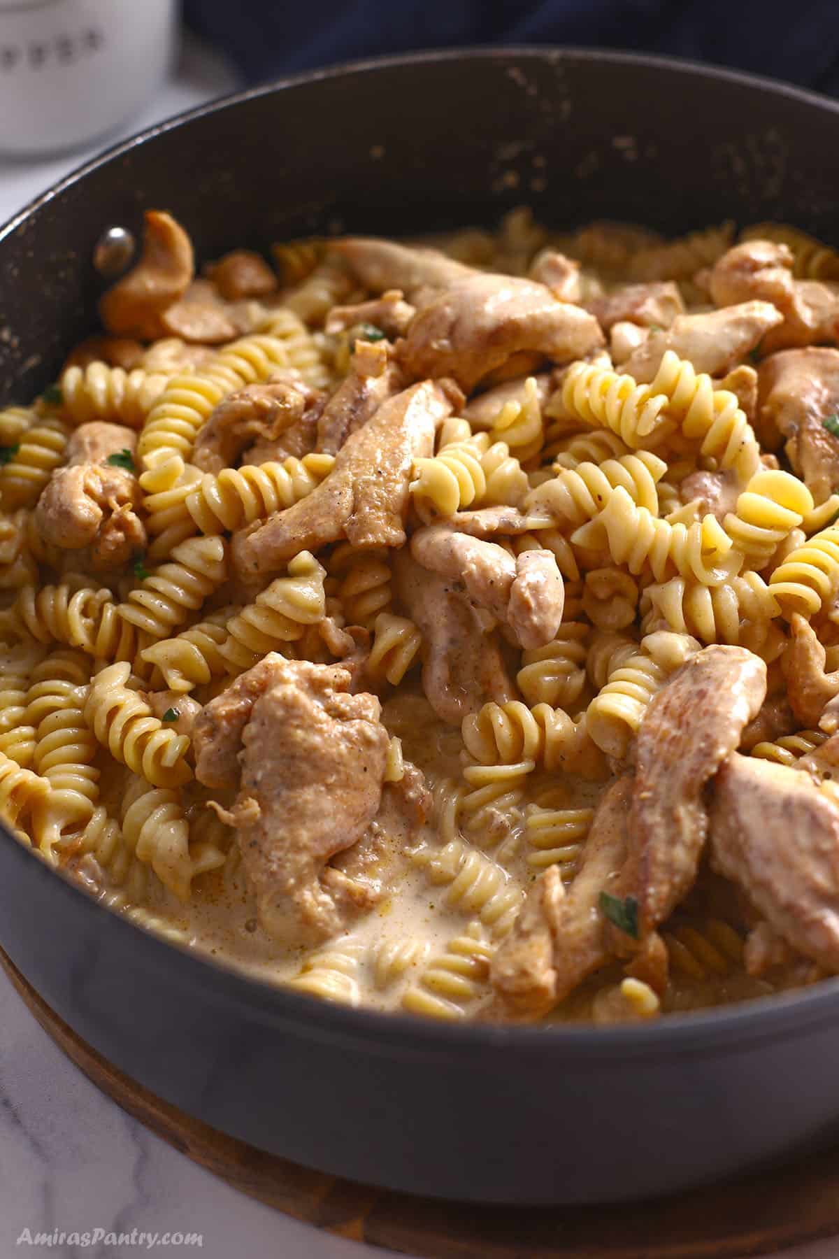 A close up image of a large skillet with chicken and pasta.