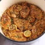 Slices of cooked chicken on a large pot over lemon rice.