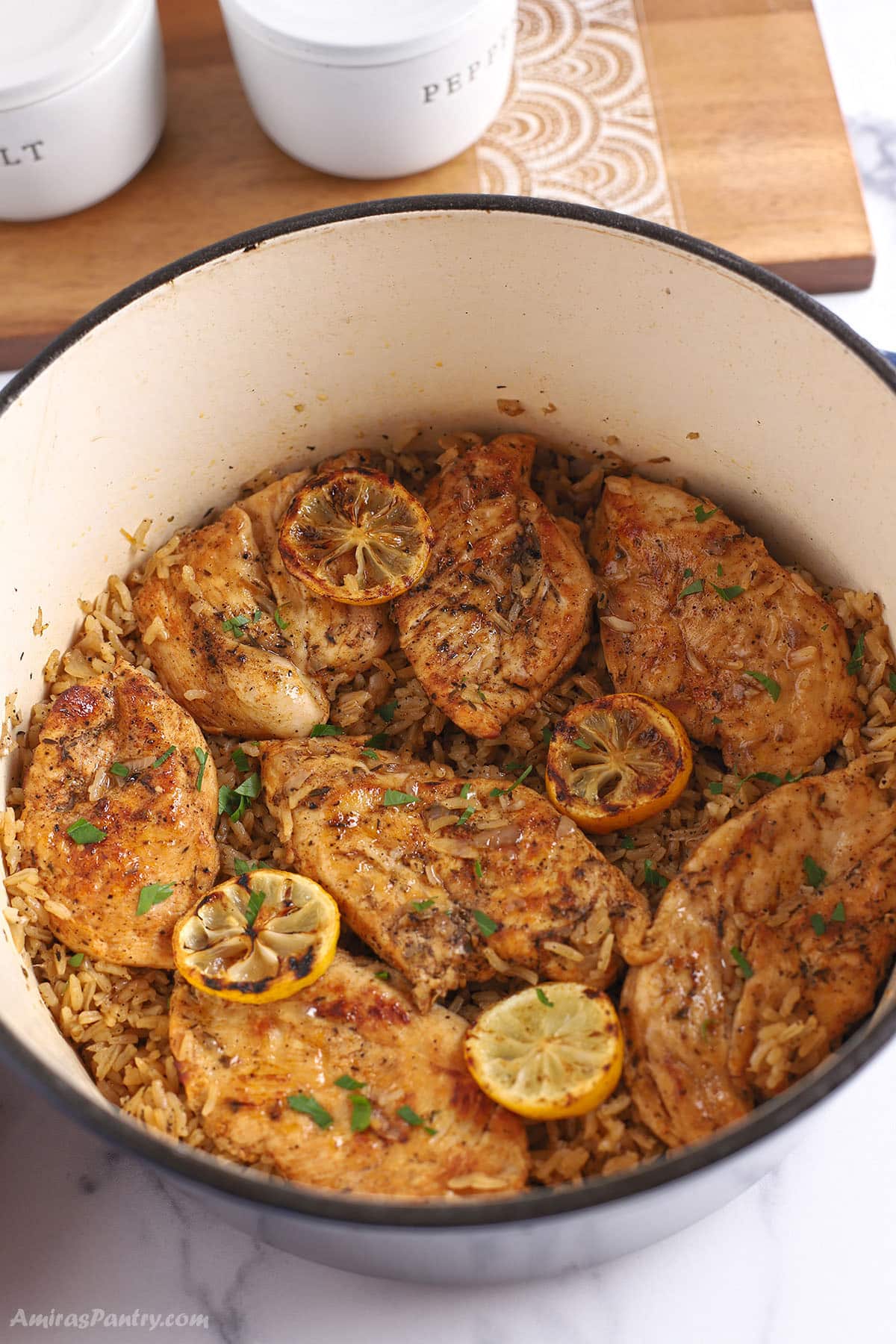 An overhead image of a dutch oven with lemon chicken and rice garnished with sliced lemons.
